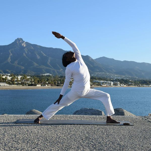 Man stretching outdoors by the sea, looking peaceful and flexible.